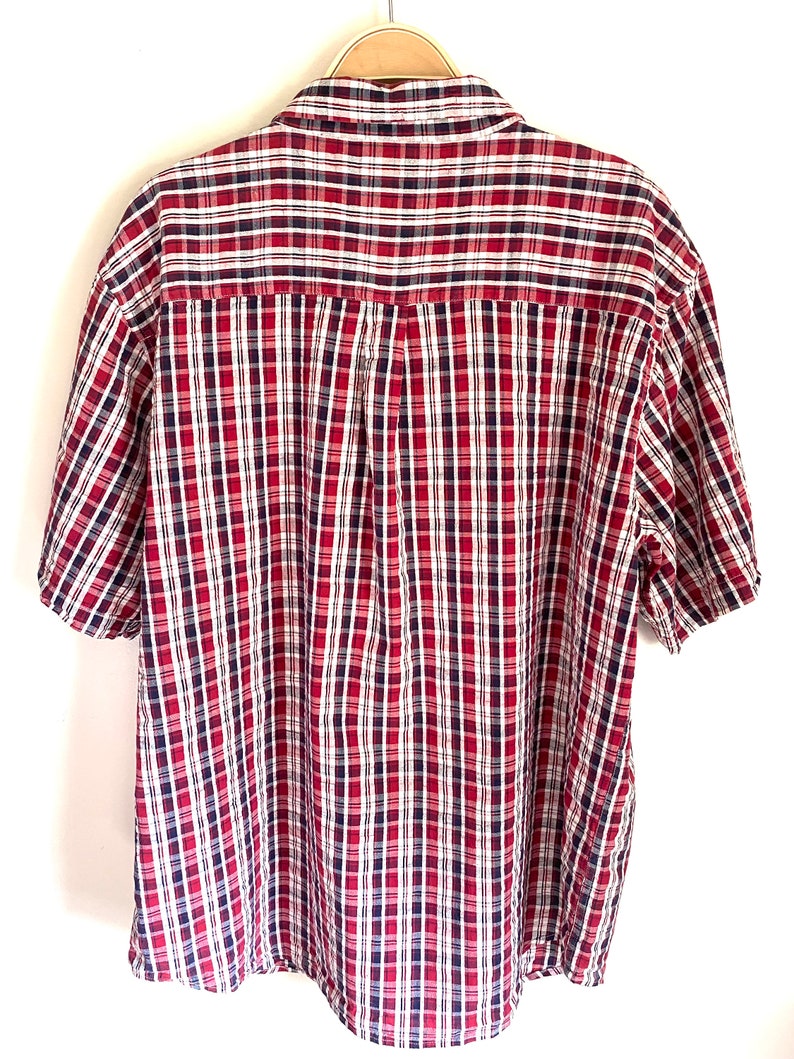 May include: A red, white, and blue plaid short-sleeved button-down shirt.
