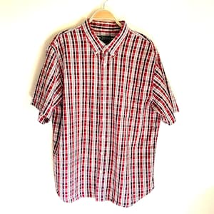 May include: A red, white, and blue plaid short-sleeved button-down shirt. The shirt has a pocket on the left side.