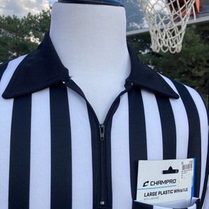 May include: Black and white striped referee shirt with a zipper and a pocket. The pocket contains a package of a Champro large plastic whistle with lanyard.