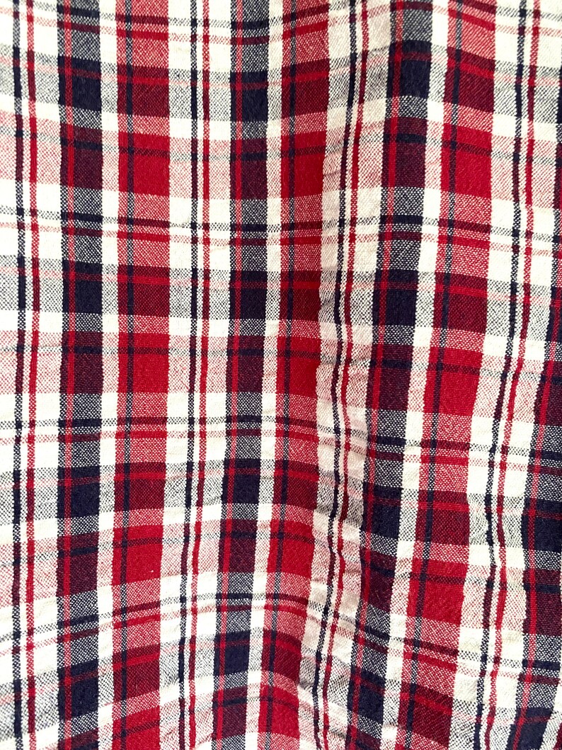 May include: Red, white, and black plaid fabric with a woven texture.