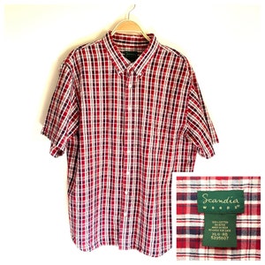 May include: Red, white, and blue plaid short-sleeved button-down shirt with a pocket on the left chest. The shirt is labeled "Scandia Woods" and has the size "XLG-RG" and the number "5335607" printed on the label.