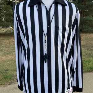 May include: Black and white striped referee shirt with a zipper and a whistle on a black lanyard. The shirt has a small pocket on the left chest and a logo on the right sleeve.