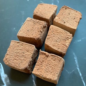 Puede incluir: Seis cubos de forma cuadrada, de color marr&oacute;n claro y con textura, dispuestos en un grupo. Cada cubo tiene una superficie mate y porosa con un aspecto ligeramente irregular y granulado, similar a un material seco y terroso.