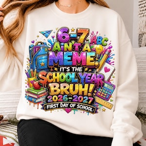 May include: A cream-coloured crewneck sweatshirt featuring a vibrant, multi-coloured graphic print with school supplies including a backpack, books, pencils, and a calculator. The text reads 6-7 AIN'T A MEME. IT'S THE SCHOOL YEAR BRUH! 2026-2027 FIRST DAY OF SCHOOL.