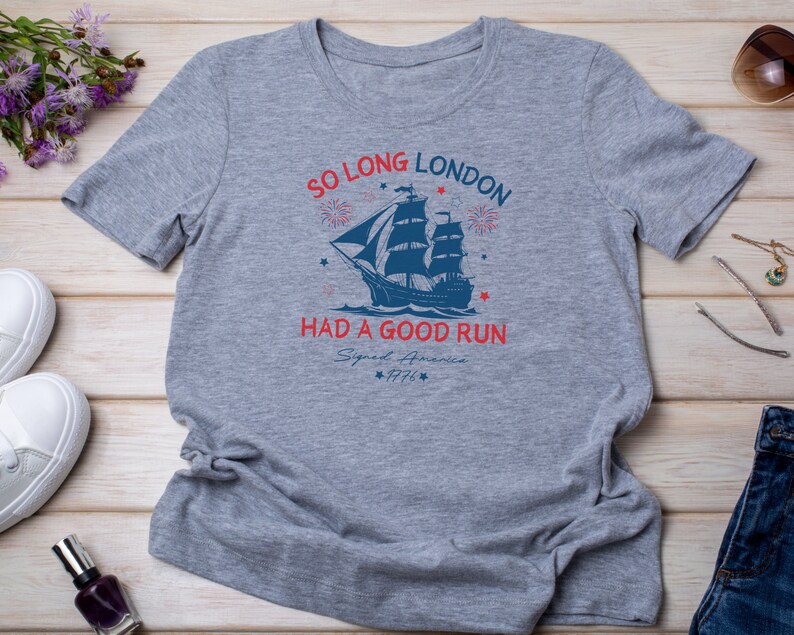 May include: Gray t-shirt with a blue and red graphic of a ship sailing away from fireworks. The text reads "So Long London Had a Good Run Signed America 1776".