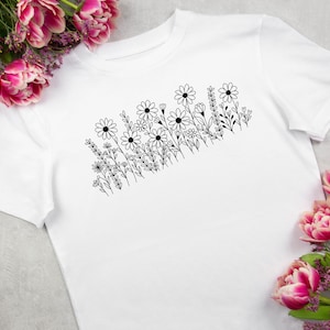 May include: A white t-shirt with a black line drawing of a cluster of flowers and leaves.