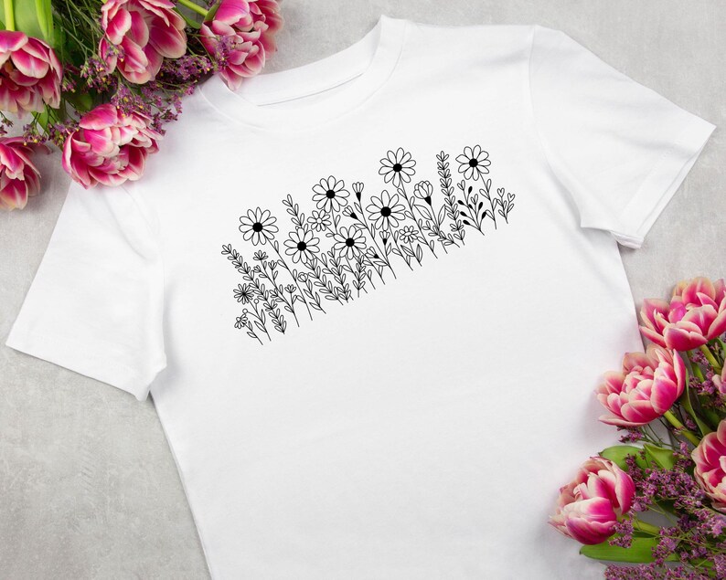 May include: A white t-shirt with a black line drawing of a cluster of flowers and leaves.