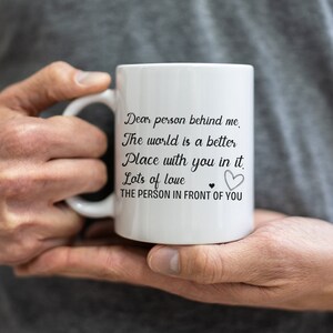 Pode incluir: Caneca de cer&acirc;mica branca com texto preto que diz "Querida pessoa atr&aacute;s de mim, O mundo &eacute; um lugar melhor com voc&ecirc; nele. Muito amor &hearts; A PESSOA NA FRENTE DE VOC&Ecirc;".