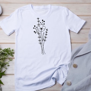 May include: White t-shirt with a black line drawing of a bouquet of flowers.