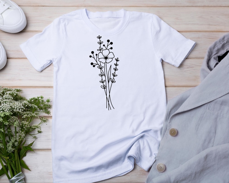 May include: White t-shirt with a black line drawing of a bouquet of flowers.