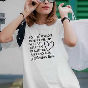 Pode incluir: Camiseta branca com um gr&aacute;fico preto que diz "To the person behind me: You are amazing, beautiful and enough. Remember that."
