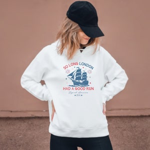 May include: White hoodie with a blue and red graphic of a ship with the text "So Long London Had a Good Run Signal America 1776".