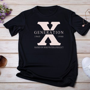 May include: Black t-shirt with a pink "X" graphic and the text "GENERATION 1965 1980 RAISED ON HOSE WATER & NEGLECT"