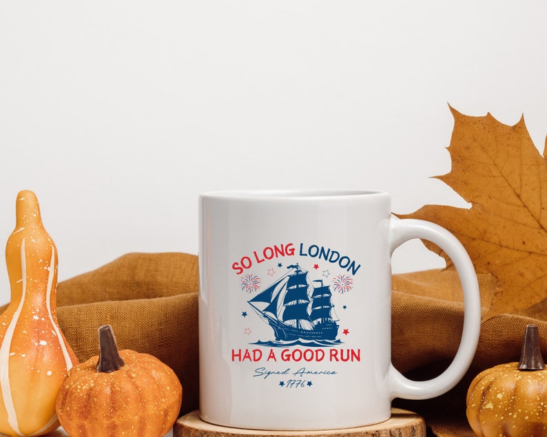 May include: White ceramic coffee mug with a blue and red graphic of a ship sailing away from fireworks. The text reads "So Long London Had a Good Run Signed America 1776".
