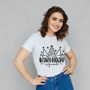 May include: White t-shirt with a black graphic of a crown with the text "Birthday Squad" underneath.