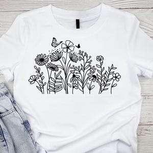 May include: White t-shirt with a black line drawing of a cluster of flowers and a butterfly.