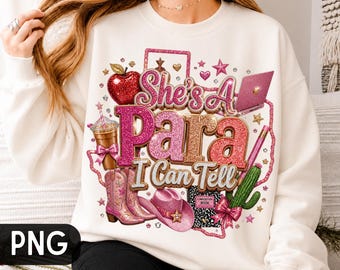 Puede incluir: Una sudadera de manga larga color crema con un estampado gráfico que incluye el texto "She's A Para I Can Tell". El diseño presenta una manzana roja, una computadora portátil rosa, un café, botas vaqueras rosas, un sombrero vaquero rosa, un cactus y un cuaderno.