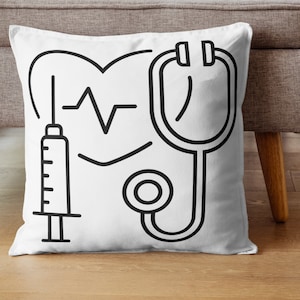 May include: White throw pillow with black line drawings of a heart with a heartbeat line, a stethoscope, and a syringe.