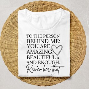 Pode incluir: Camiseta branca com texto preto que diz "Para a pessoa atr&aacute;s de mim: Voc&ecirc; &eacute; incr&iacute;vel, linda e suficiente. Lembre-se disso."