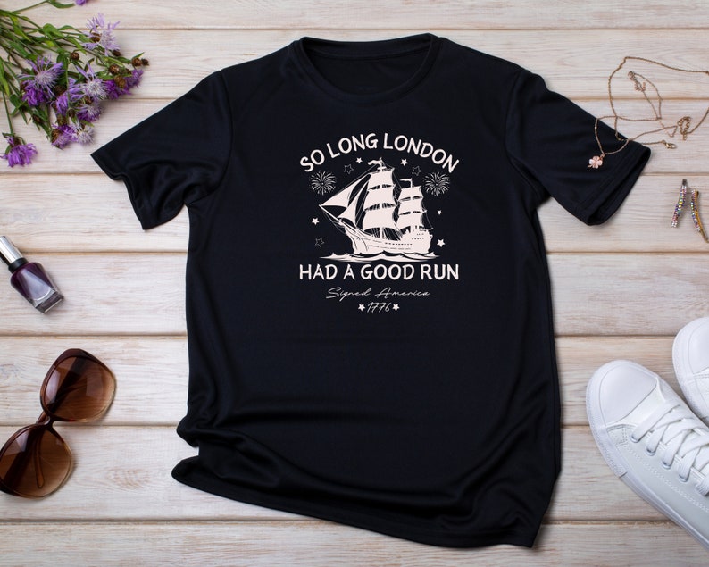 May include: Black t-shirt with a white graphic of a ship sailing away with fireworks and stars. The text reads "So Long London Had A Good Run Signed America 1776".