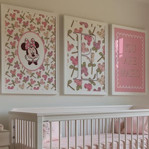 May include: A nursery with a white crib, dresser, and armchair. Pink bedding and curtains complement the floral artwork and rug. A tufted ottoman and a lamp complete the room's decor.