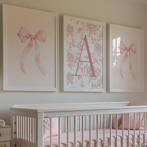 May include: A nursery with a white crib, dresser, and armchair. Pink bedding and artwork with bows and floral prints decorate the room. A tufted ottoman and a lamp with a decorative base complete the space.