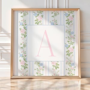 May include: A framed floral print featuring a large pink letter "A" on a white background. The frame is gold, and the print has a striped background with pink and blue roses and greenery. The overall aesthetic is vintage and feminine.