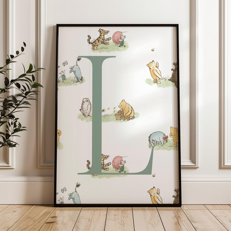 May include: A framed print featuring the letter "L" in a soft green hue, adorned with illustrations of Winnie the Pooh and friends. The artwork includes characters like Tigger, Piglet, and Eeyore, set against a light background.