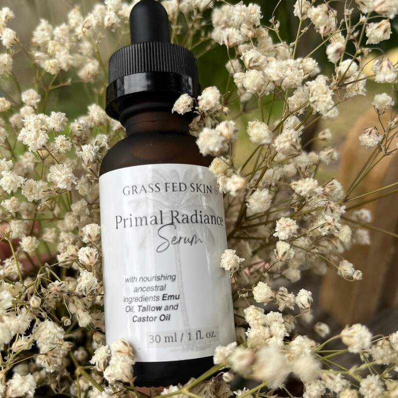May include: A brown glass bottle with a white label that reads "GRASS FED SKIN CARE Primal Radiance Serum with nourishing ancestral ingredients Emu Oil, Tallow and Castor Oil 30 ml / 1 fl. oz."