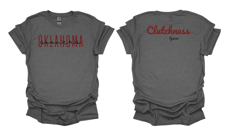 K&ouml;nnte beinhalten: Dunkelgraues T-Shirt mit dem Aufdruck "OKLAHOMA Sooners" in Rot und Schwarz auf der Vorderseite. Auf der R&uuml;ckseite des Shirts steht "Clutchness Garre" in Rot.