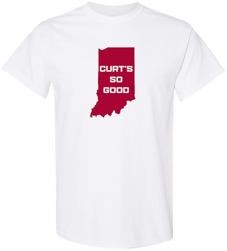 May include: White t-shirt featuring a red outline of the state of Indiana. The text "CURT'S SO GOOD" is printed in white within the state's borders. The shirt is made of a soft material and has short sleeves.