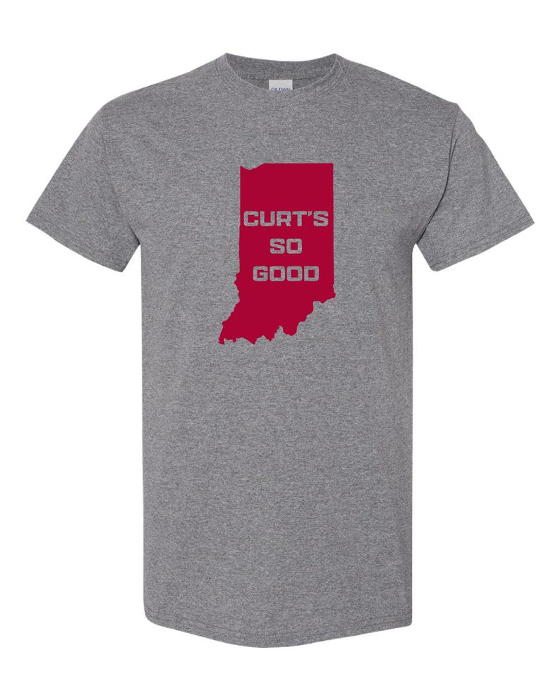 May include: A heather gray t-shirt featuring a red outline of the state of Indiana. The text "CURT'S SO GOOD" is printed in white within the state's borders. The shirt has short sleeves and a crew neck.