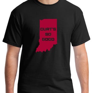 May include: Black t-shirt featuring a red outline of the state of Indiana with the text "CURT'S SO GOOD" in red block letters. The shirt is a crew neck style.