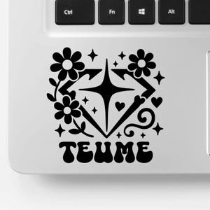 Puede incluir: Una pegatina en blanco y negro en un portátil. Presenta un diseño estilizado con flores, estrellas y la palabra "TEUME". El diseño tiene una forma geométrica con flechas y corazones.