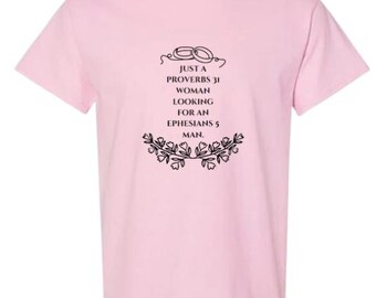 May include: Pink t-shirt with black text that reads "Just a Proverbs 31 woman looking for an Ephesians 5 man."  The text is surrounded by a floral design.