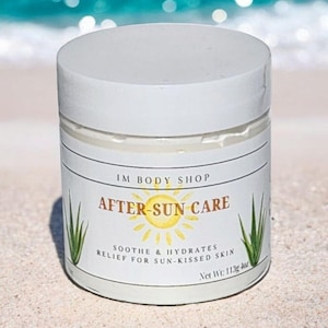 May include: White jar of after-sun care lotion with a yellow sun and green aloe vera leaves on the label. The label reads "IM BODY SHOP AFTER-SUN CARE SOOTHE & HYDRATES RELIEF FOR SUN-KISSED SKIN Net Wt: 113g 4oz".