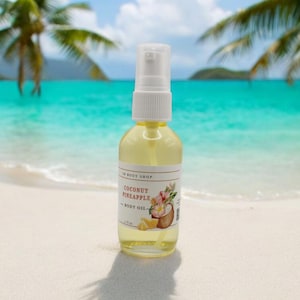 May include: A clear glass bottle of coconut pineapple body oil with a white pump top. The label features a watercolor illustration of a coconut, pineapple, and flowers. The background is a tropical beach scene with palm trees and turquoise water.