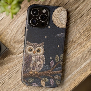 May include: A phone case with an owl design, set against a dark blue night sky with stars and a full moon. The owl is illustrated in brown, purple, and beige tones, perched on a branch. The moon is a light beige colour.