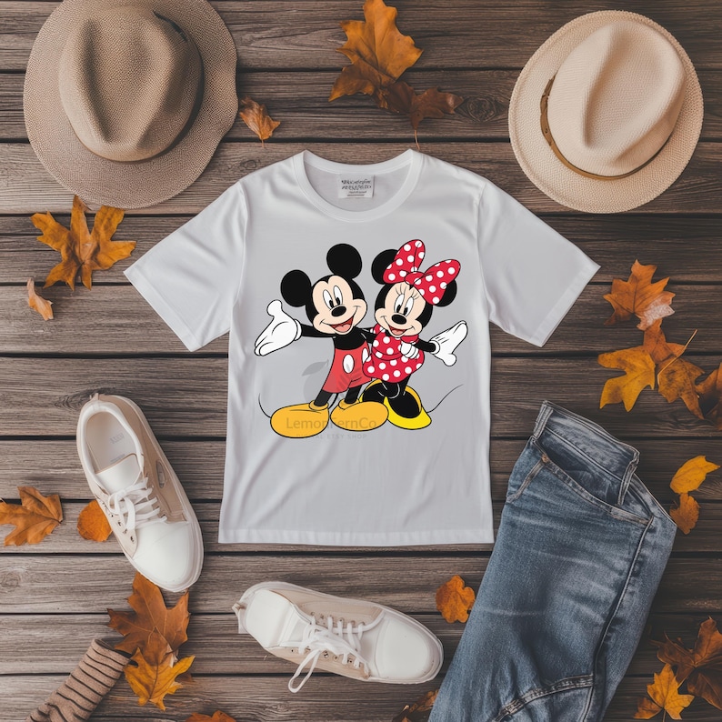 Może przedstawiać: Biała koszulka z postaciami z kresk&oacute;wek Mickey i Minnie Mouse. Miki ma na sobie czerwone szorty, a Minnie czerwoną sukienkę w kropki. Koszulka jest połączona z niebieskimi dżinsami, białymi trampkami i dwoma beżowymi kapeluszami. Na koszulce znajduje się napis "Lemon mc".