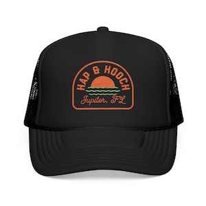 May include: Black trucker hat with a curved brim and mesh back. The front features an orange and green patch with the words "HAP & HOOCH" above a sunset and the text "Jupiter, FL".