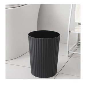 May include: A black, cylindrical waste bin with a ribbed texture. The bin is made of plastic and has a smooth, rounded top.