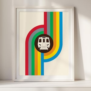 May include: A framed wall art print featuring a centered dark brown circle containing a white front-facing train graphic. The train is surrounded by vertical and curved stripes in red, gray, green, yellow, orange, and blue on a cream background.