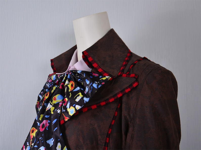 May include: A brown jacket with a red and black checkered trim. The jacket has a large, ruffled collar with a colorful floral pattern.