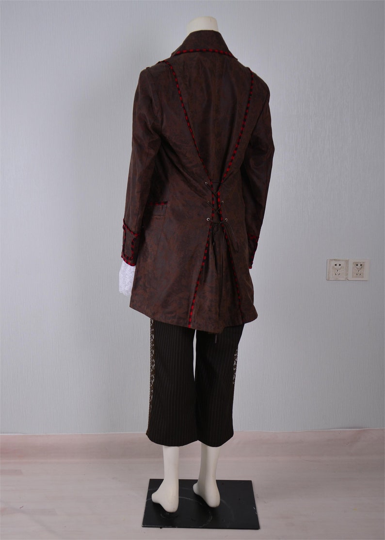 May include: A brown jacket with red trim and a lace-up back. The jacket is worn over black pants with a white shirt underneath.