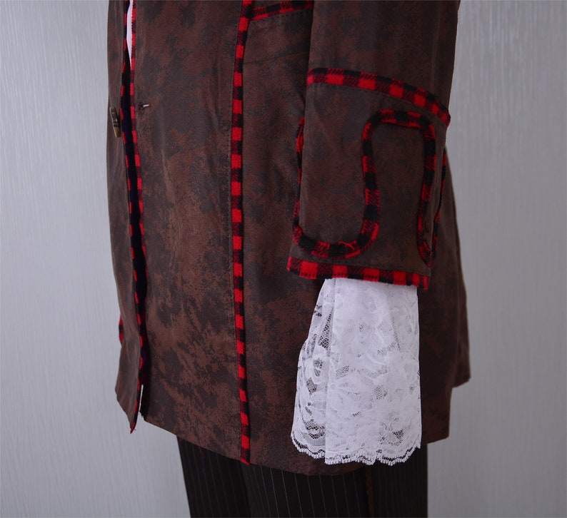 May include: A brown jacket with red and black plaid trim. The jacket has a single button closure and a white lace trim on the sleeve.