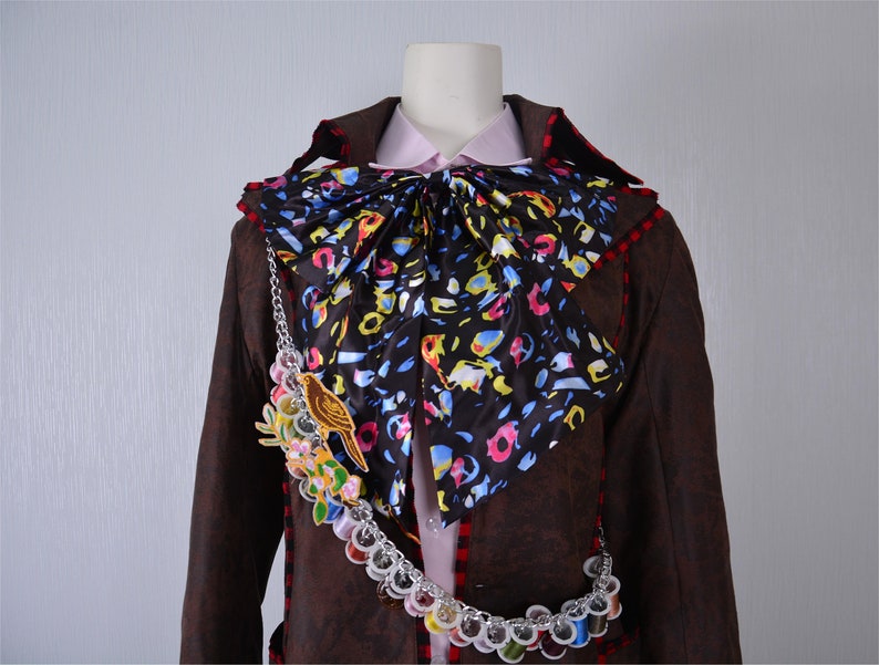 May include: A brown jacket with a colorful patterned bow tie and a chain with colorful beads and a bird charm.