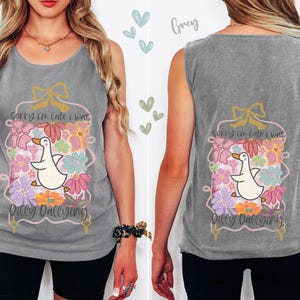 May include: A gray tank top with a floral and duck graphic. The graphic includes the text "Sorry I'm late I was Dilly Dallying." The design features a white duck, flowers, and a gold bow.