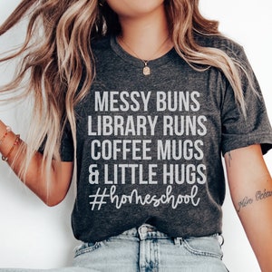 May include: A gray t-shirt with the text "Messy Buns Library Runs Coffee Mugs & Little Hugs #homeschool" printed in white.