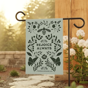 May include: A green garden flag with a floral design and the text "Rejoice Always" with the scripture reference "1 Thessalonians 5:16".