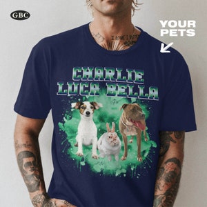 May include: A navy blue t-shirt with a green watercolor splatter design featuring three pets: a white dog, a brown and white dog, and a white rabbit. The names "Charlie", "Luca", and "Bella" are printed in white on the shirt.